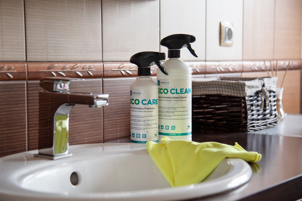 about-01 Eco-friendly cleaning products displayed on a bathroom sink with tiles and a basket.